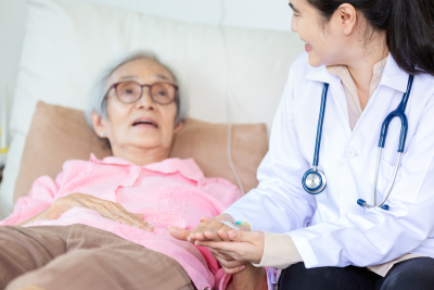 elderly woman lying in bed with her doctor